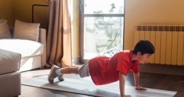 Child doing pushup at home on mat.