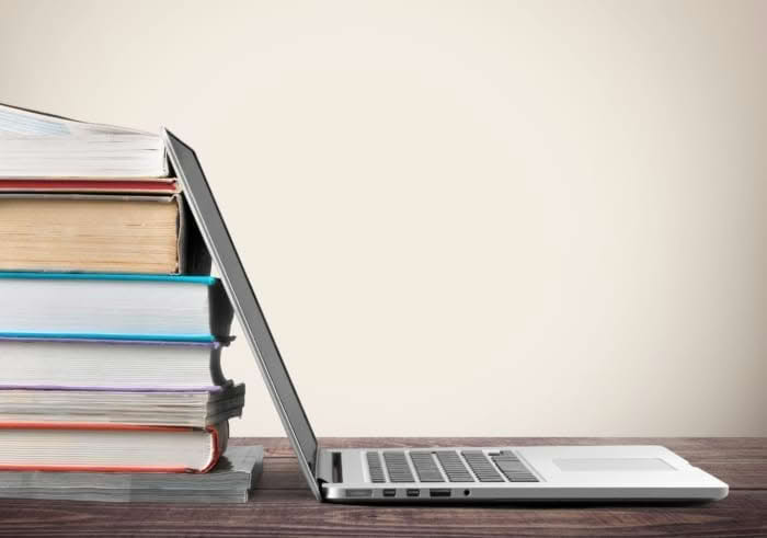 Stack of books with a laptop on wooden table